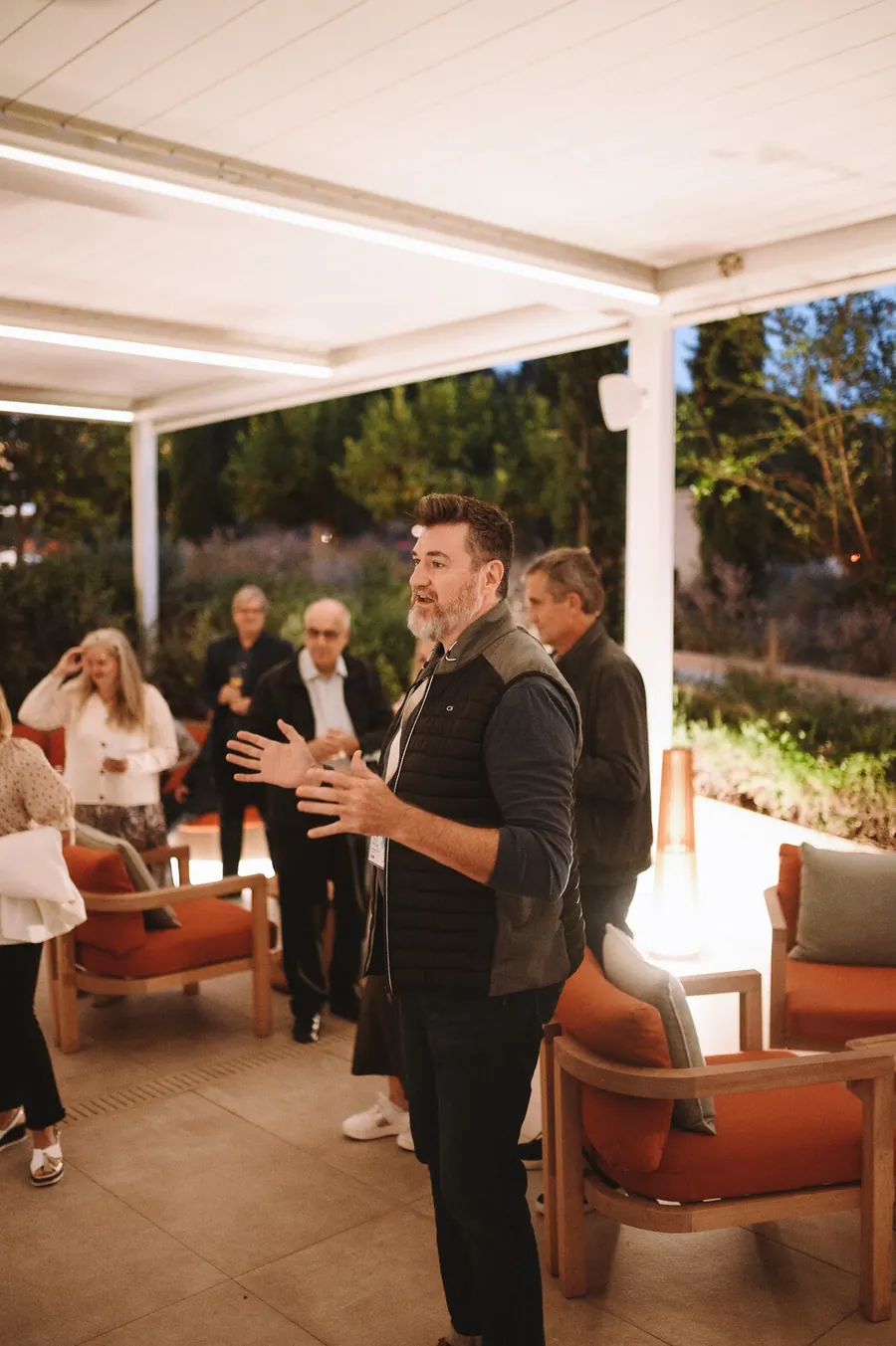 Tony Wood speaking during an evening discussion with a group outdoors.