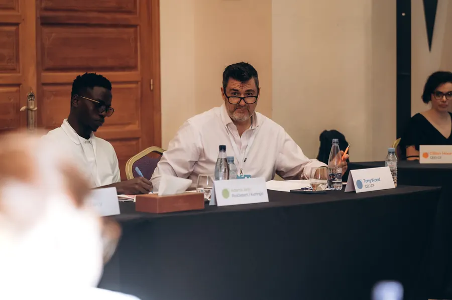 Tony Wood seated at a panel table during a workshop conversation.