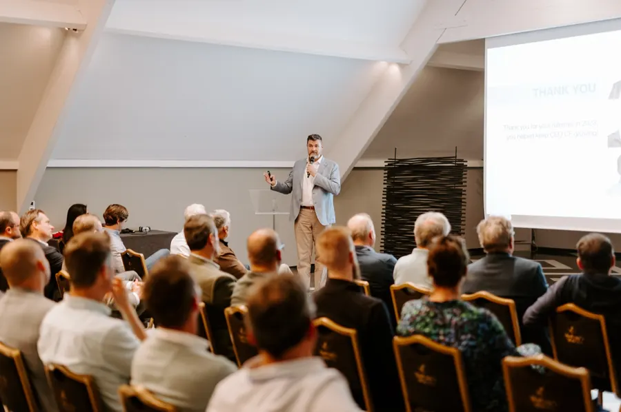 Tony Wood presenting to an audience in a conference room.